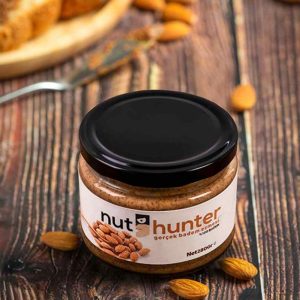 Nut Hunter %100 Şekersiz Badem Ezmesi, en yüksek kalitedeki bademlerin kimyasal işlem görmeden, tamamen doğal yöntemlerle ezilmesiyle elde edilir. İçeriği sadece %100 Bademdir. Bu ürün, bademlerin zengin lif ve protein kaynağı olma özelliğini, besin değeri kaybolmadan sofranıza taşır. 100 gramda 21 gram protein içeriğiyle besleyicidir. Üründe palm yağı, kıvam attırıcı, koruyucu, şeker ilavesi veya tatlandırıcı kesinlikle bulunmaz. Doğallığı sayesinde Ketojenik beslenmeye tamamen uygundur.