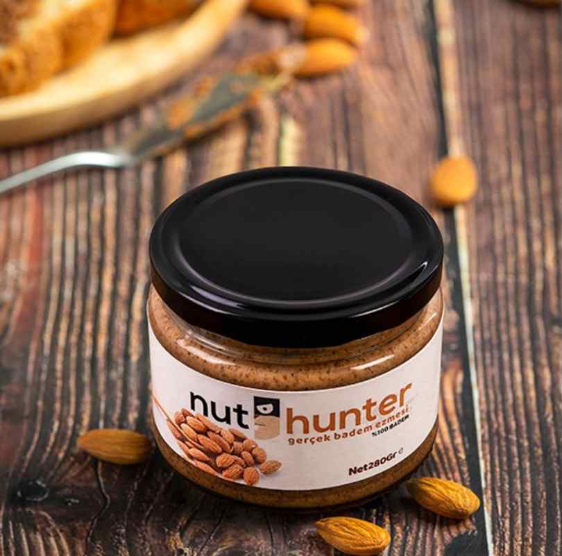 Sade Badem Ezmesi Nut Hunter %100 Şekersiz Badem Ezmesi, en yüksek kalitedeki bademlerin kimyasal işlem görmeden, tamamen doğal yöntemlerle ezilmesiyle elde edilir. İçeriği sadece %100 Bademdir. Bu ürün, bademlerin zengin lif ve protein kaynağı olma özelliğini, besin değeri kaybolmadan sofranıza taşır. 100 gramda 21 gram protein içeriğiyle besleyicidir. Üründe palm yağı, kıvam attırıcı, koruyucu, şeker ilavesi veya tatlandırıcı kesinlikle bulunmaz. Doğallığı sayesinde Ketojenik beslenmeye tamamen uygundur.